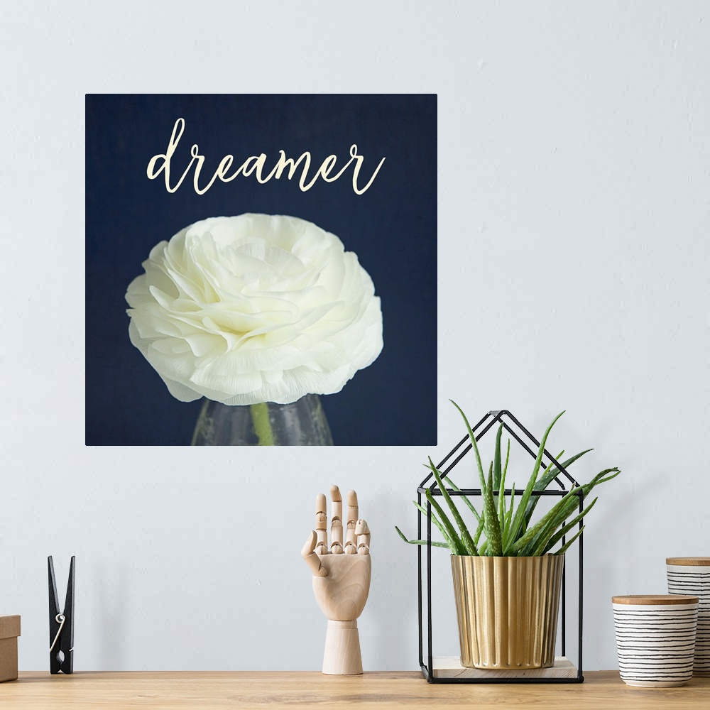 A bohemian room featuring A white flower in a glass vase with the word "dreamer" above it.