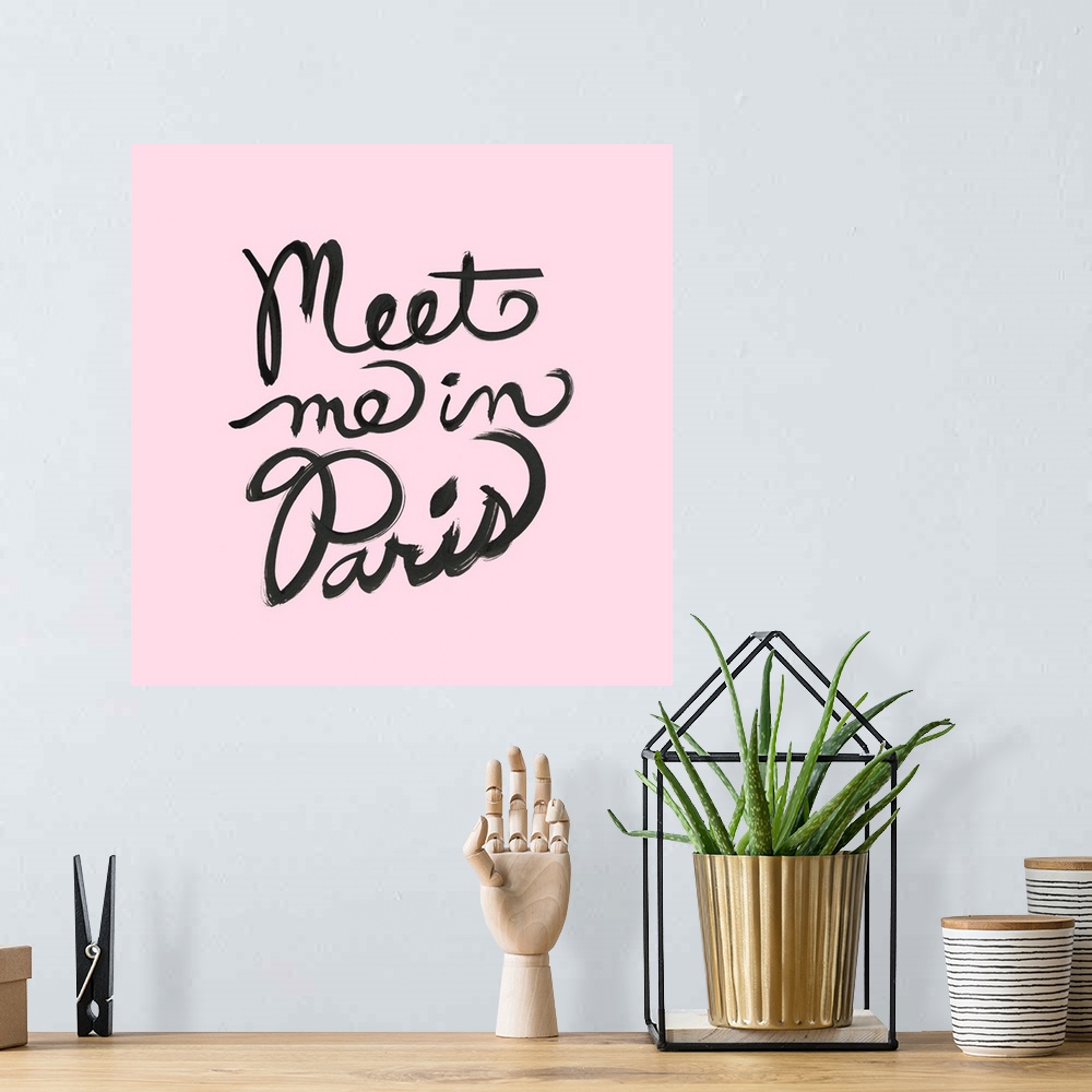 A bohemian room featuring "Meet Me In Paris" hand lettered in black on a pastel pink background.