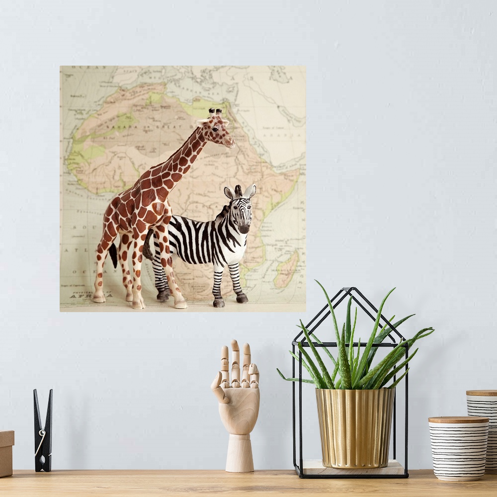 A bohemian room featuring A toy giraffe and zebra with a vintage map backdrop.