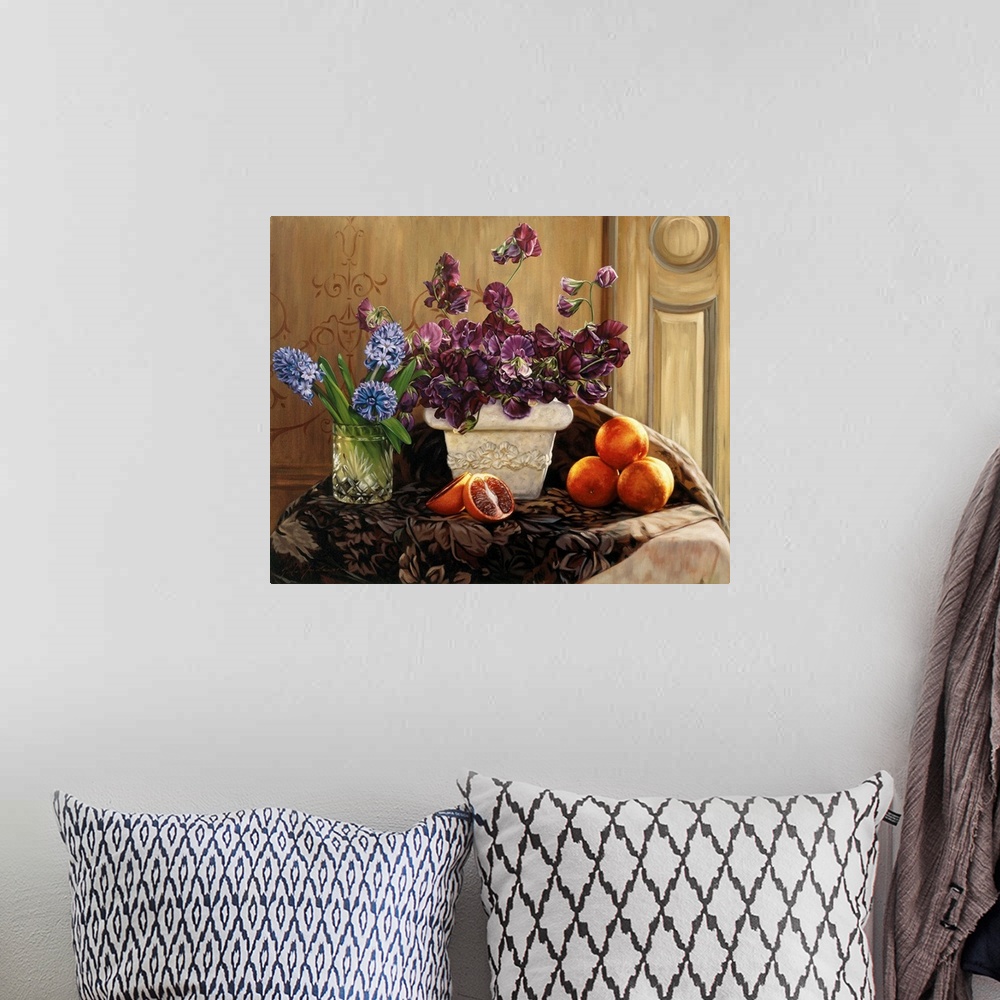 A bohemian room featuring A large white vase filled with purple flowers, one clear vase filled wtih blue flowers and blood ...