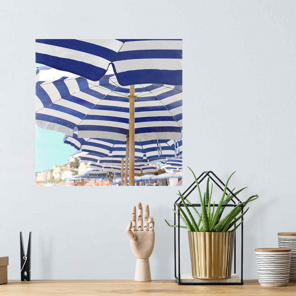 A bohemian room featuring Square decor with blue and white striped beach umbrellas lined up on the beach.