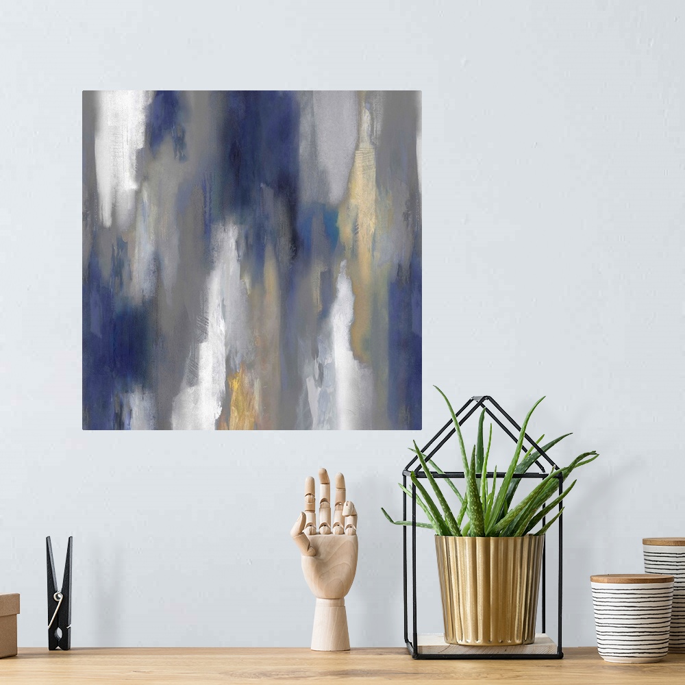 A bohemian room featuring Square abstract painting with hazy shades of blue, gray, white, and gold smearing down the canvas.