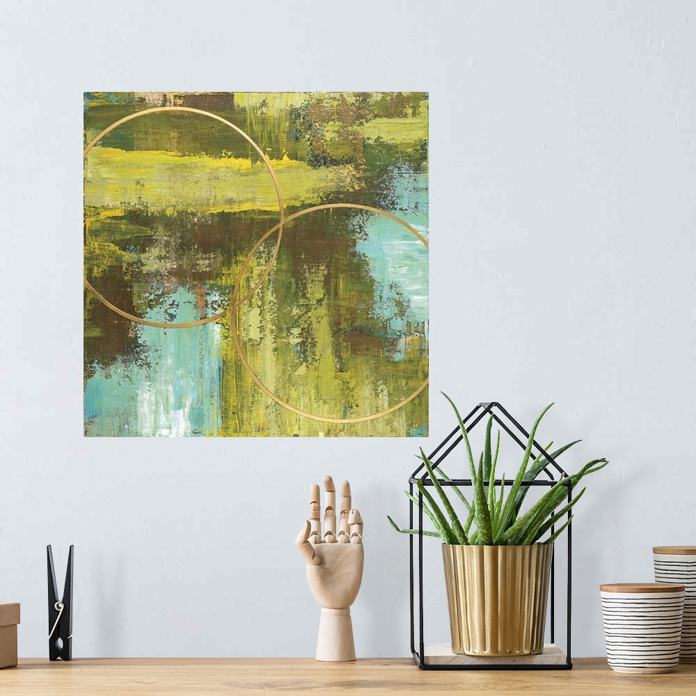 A bohemian room featuring Square abstract of two circular rings in gold with a textured background of green and blue.