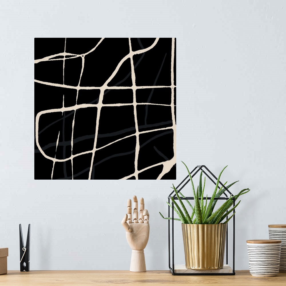 A bohemian room featuring A square abstract of beige drips of paint overlaying in varies directions with a black backdrop.