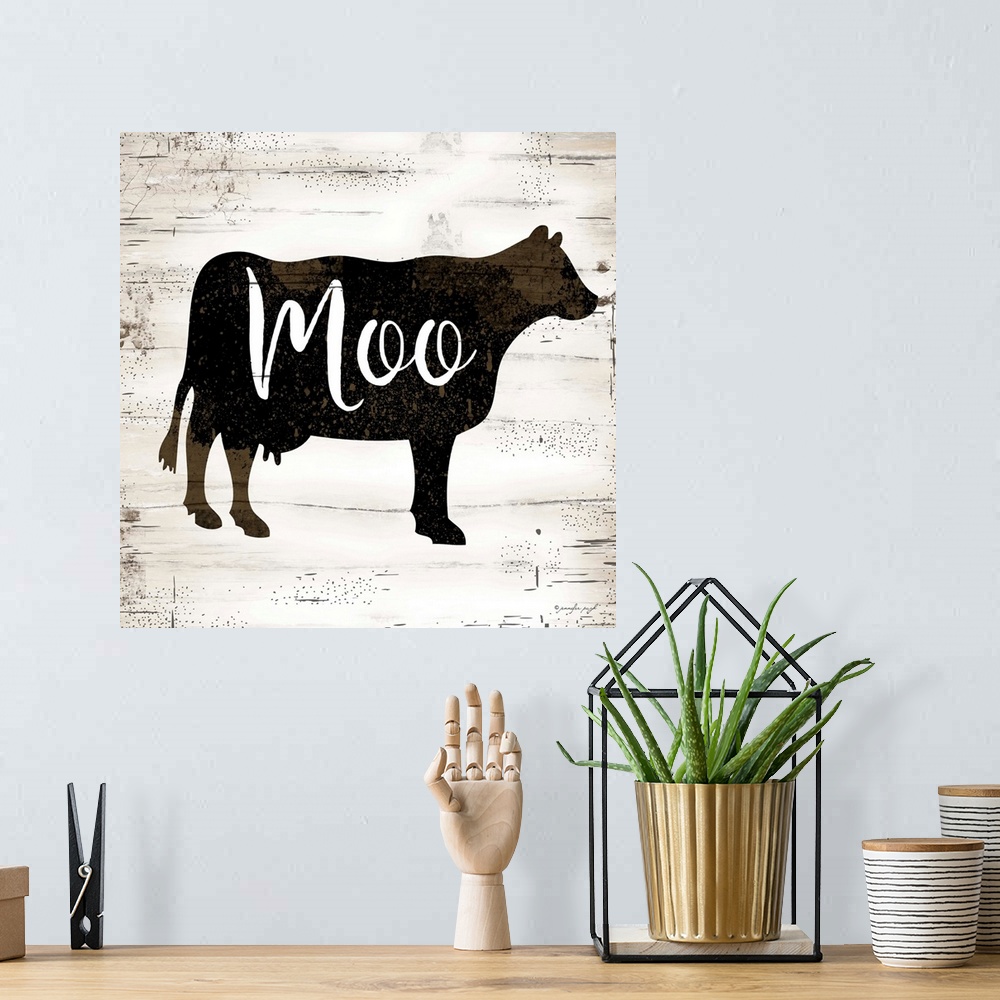 A bohemian room featuring Graphic art of the silhouette of a cow with script text overlapping it, on a a horizontally strip...