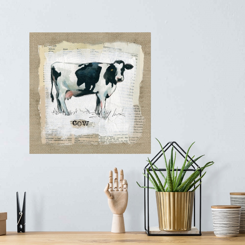 A bohemian room featuring Square burlap collage art of a cow painted on top of newspaper clippings with the word "cow" stam...