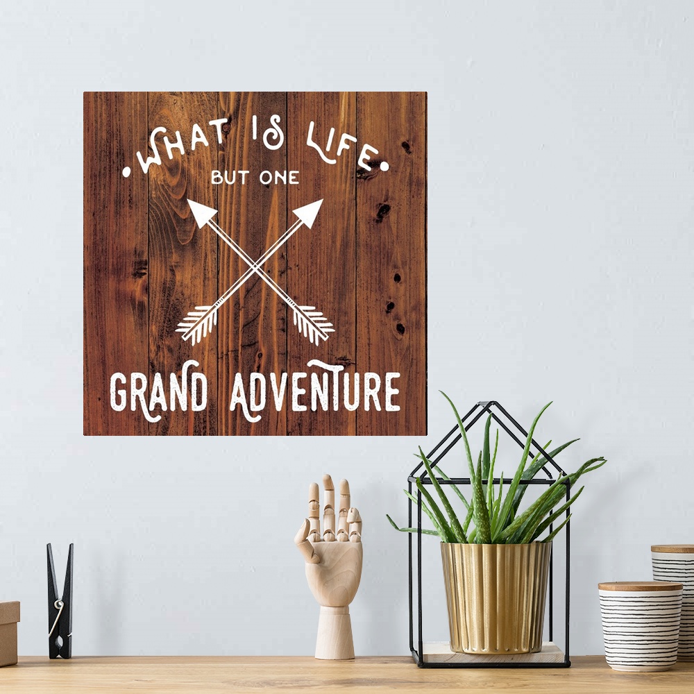 A bohemian room featuring Typography art reading "What is life but one grand adventure" with a crossed arrow design on a wo...