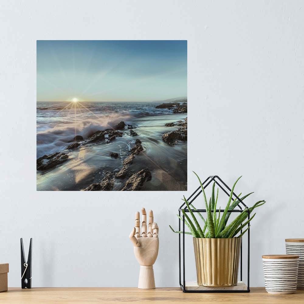 A bohemian room featuring Square photograph of ocean waves crashing on a rocky shore with the sun setting on the horizon li...