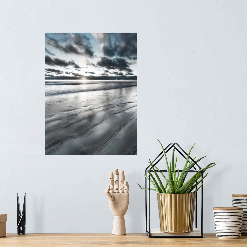 A bohemian room featuring Black, blue, and white manipulated photograph of a seascape with the sun right on the horizon line.