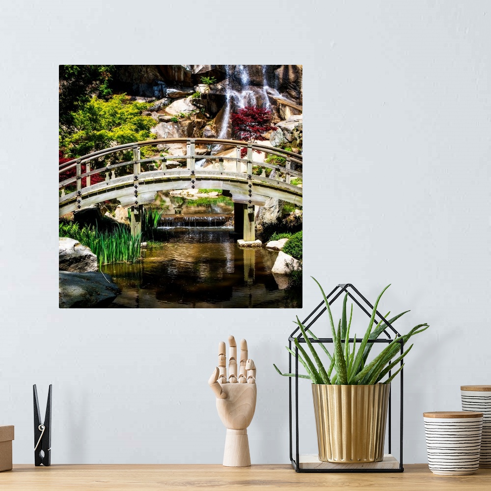 A bohemian room featuring Square photograph of a bridge over a stream with a waterfall in the background.