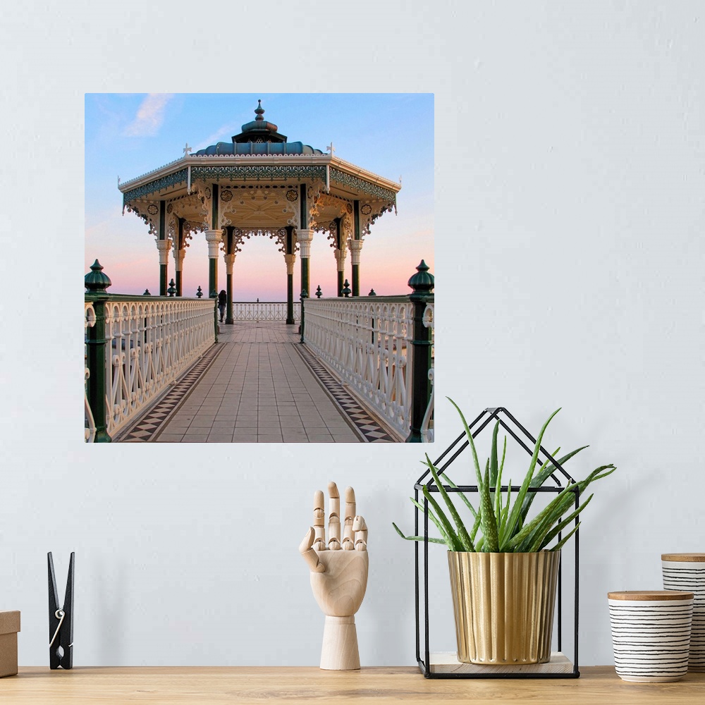 A bohemian room featuring A lone figure and an almost symmetrical shot of an ornate seaside bandstand. The sky is awash wit...