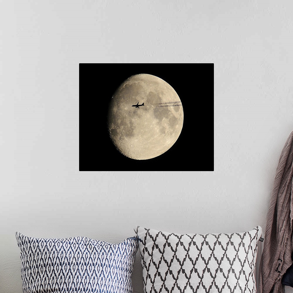 A bohemian room featuring plane crossing in front of moon.