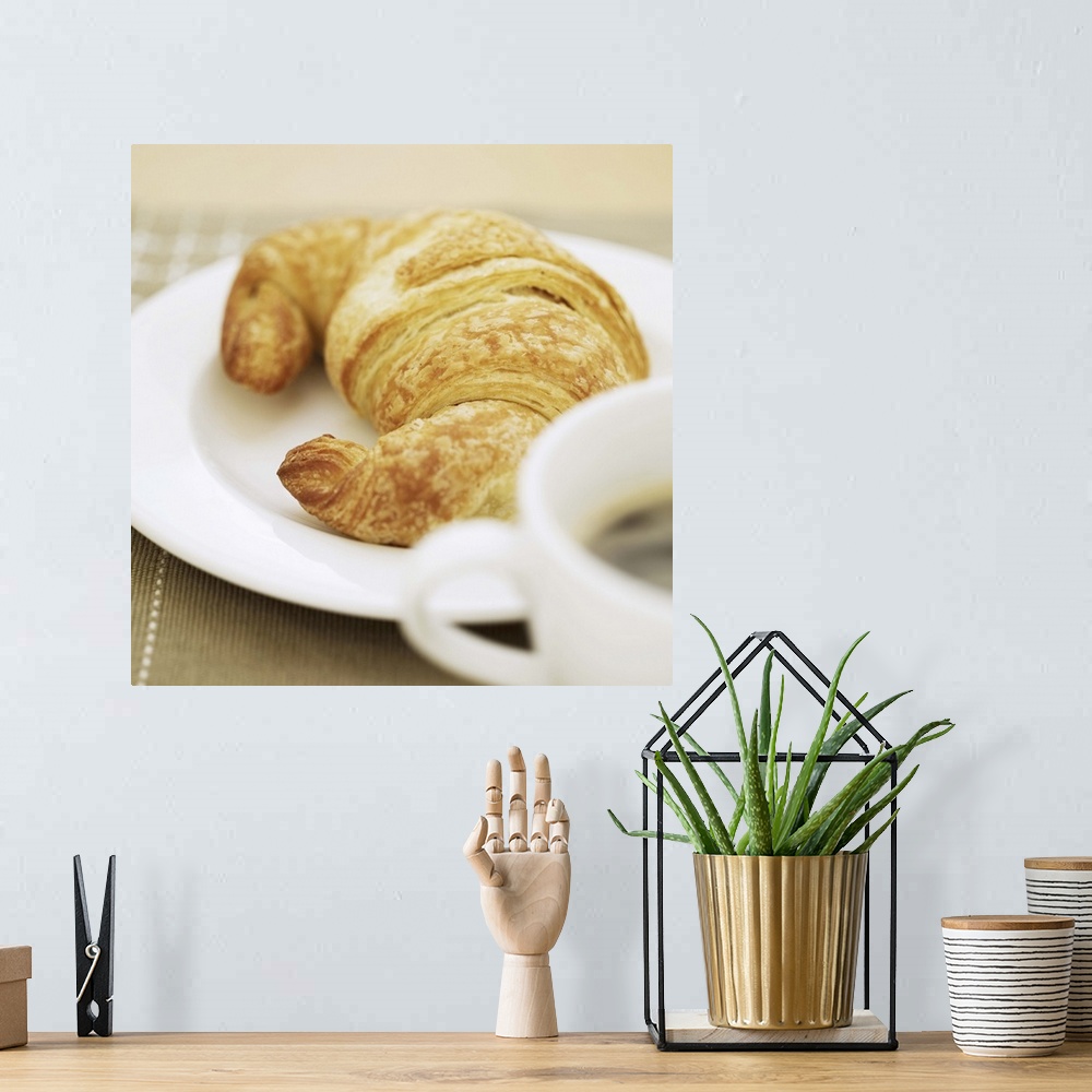 A bohemian room featuring close-up of a cup of hot black coffee and a croissant