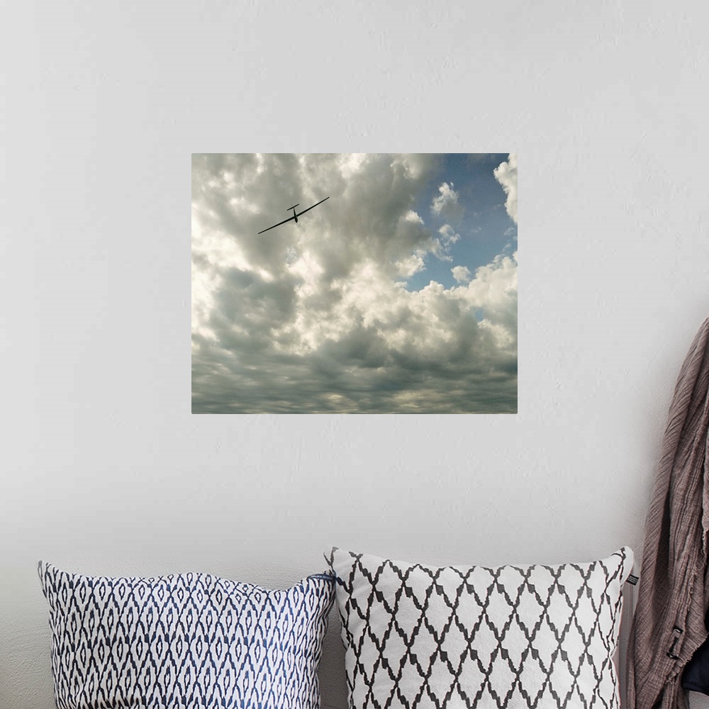 A bohemian room featuring Glider in flight against cloudy sky, low angle view