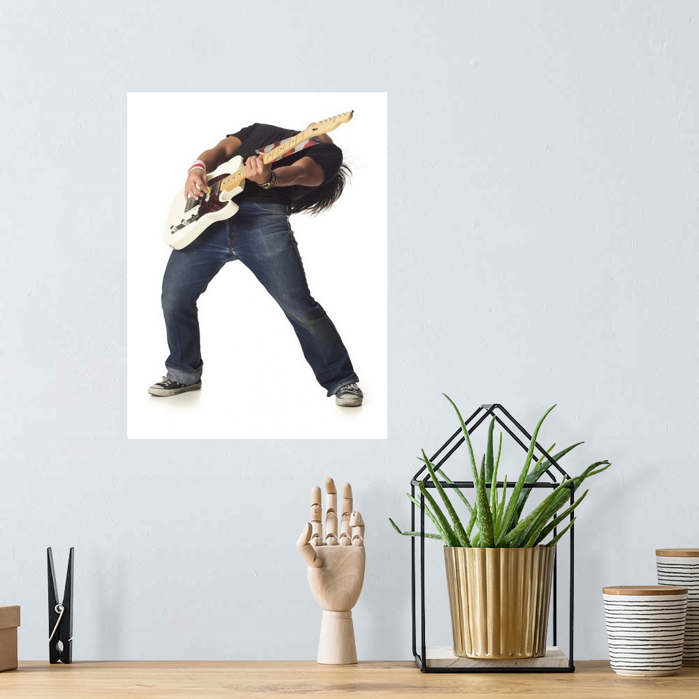 A bohemian room featuring an asian male teen in jeans and a black shirt leans back while playing an electric guitar