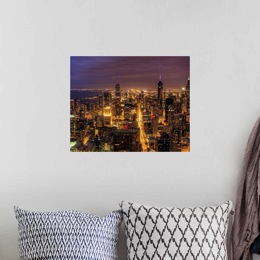 A bohemian room featuring High-angle photograph of city with buildings and streets lit up at dusk.