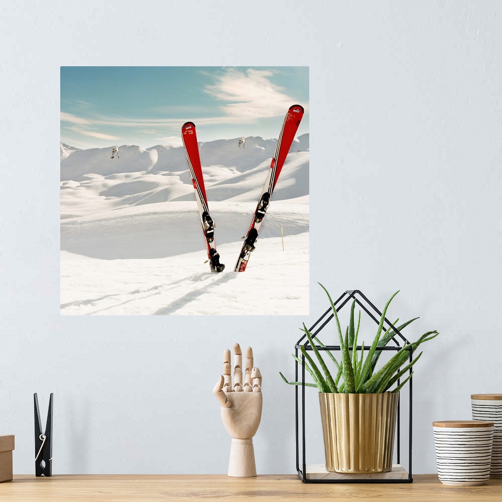 A bohemian room featuring Red pair of ski standing in snow.Mountains in background