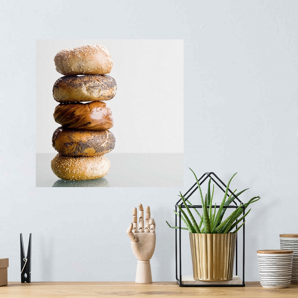 A bohemian room featuring Different types of bagels are stacked high and photographed on a glass surface.