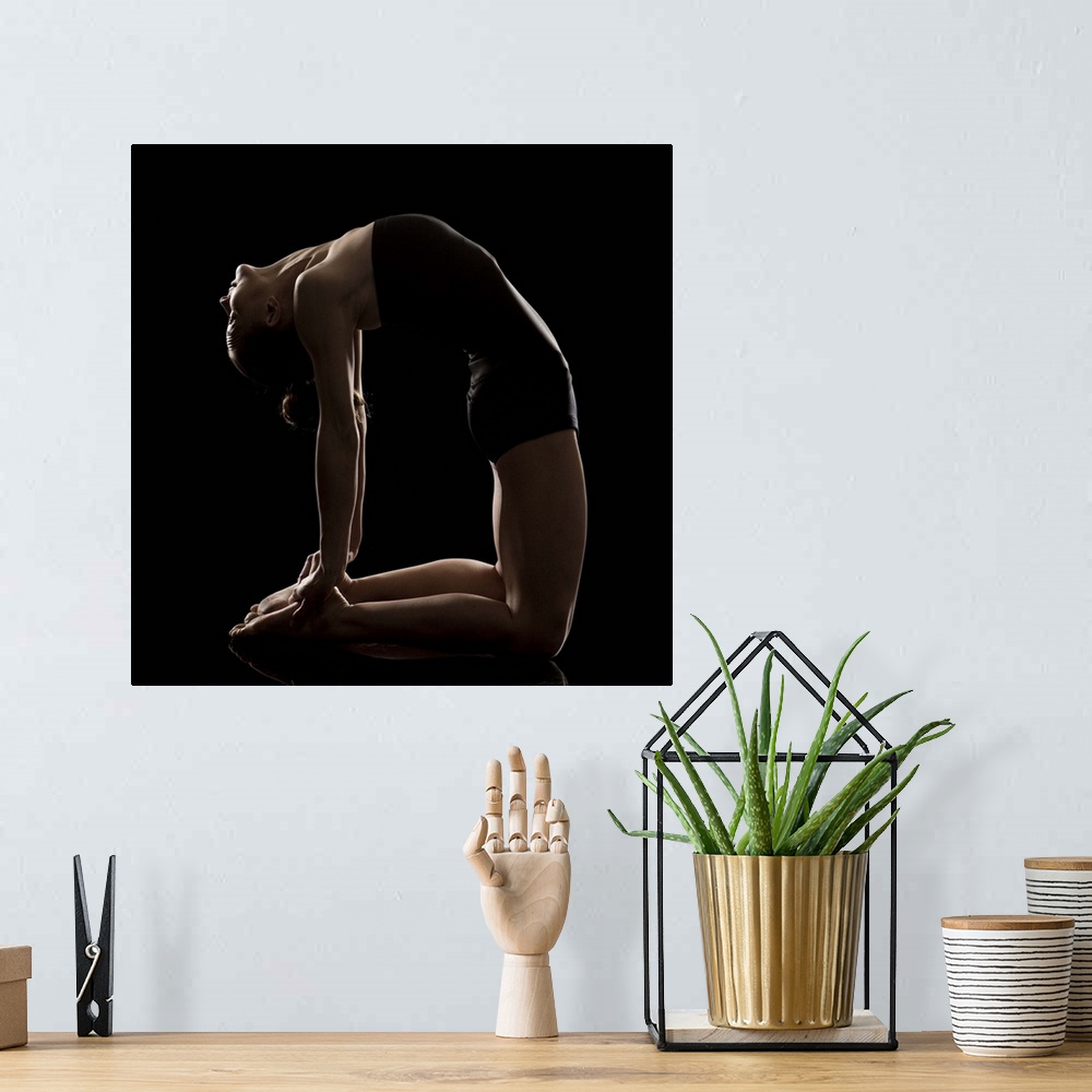 A bohemian room featuring Studio shot of young woman practicing yoga.   The camel pose, Ushtra asana.