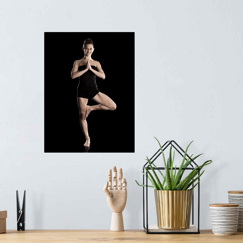 A bohemian room featuring Studio shot of young woman practicing yoga.  The tree pose, Vriksasana.