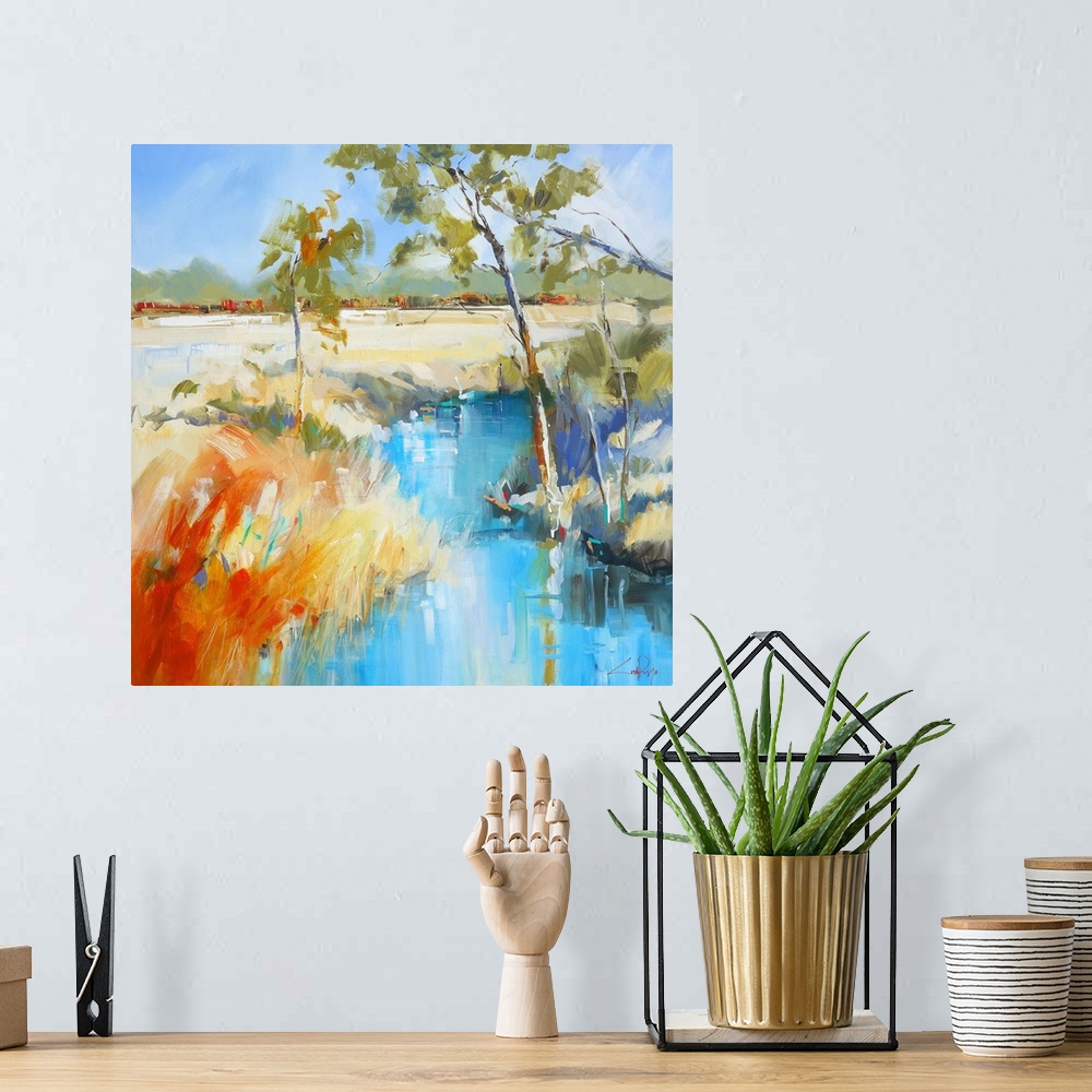 A bohemian room featuring Slender trees at the edge of a creek in a field.