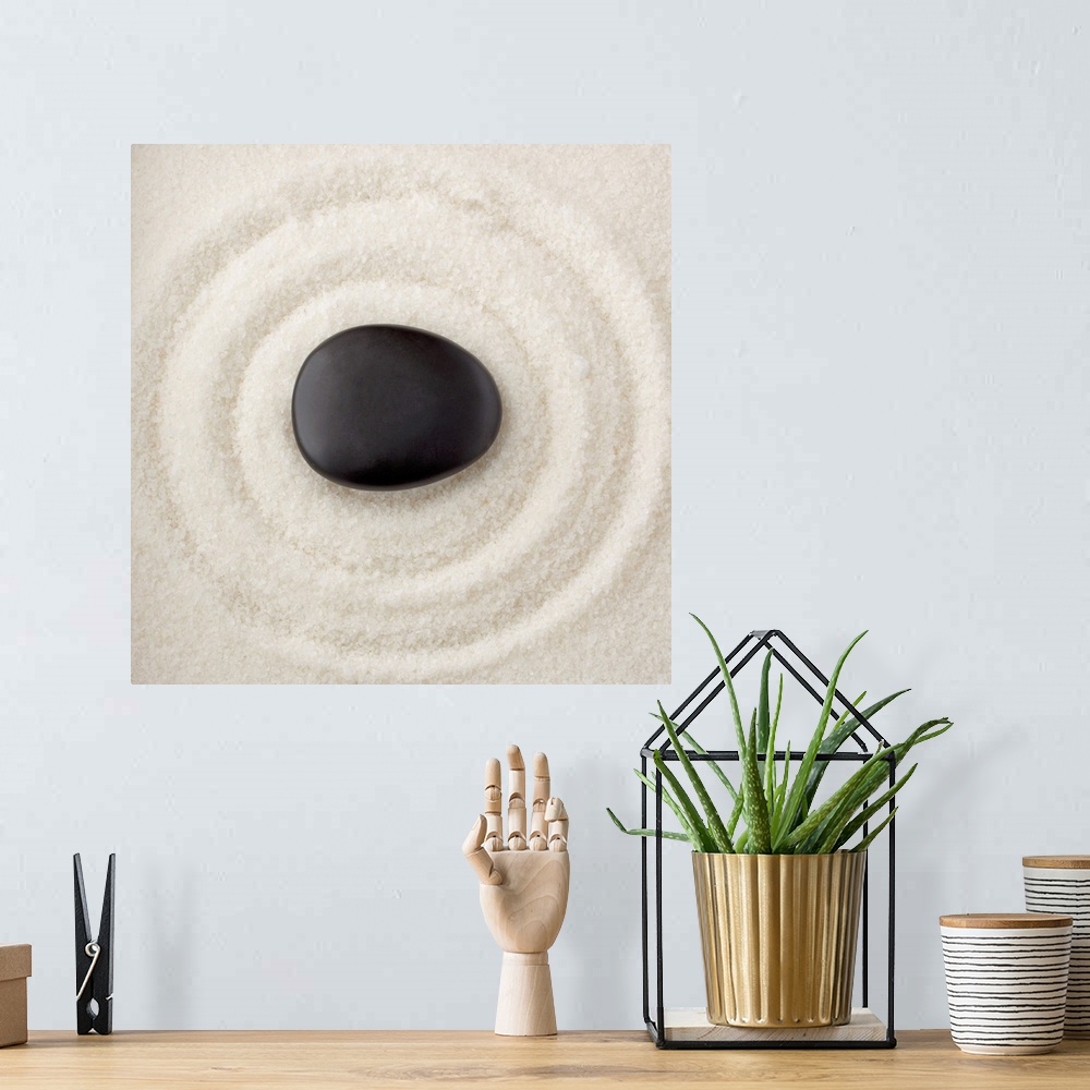 A bohemian room featuring A smooth black rock in the middle of multiple rings in the sand.