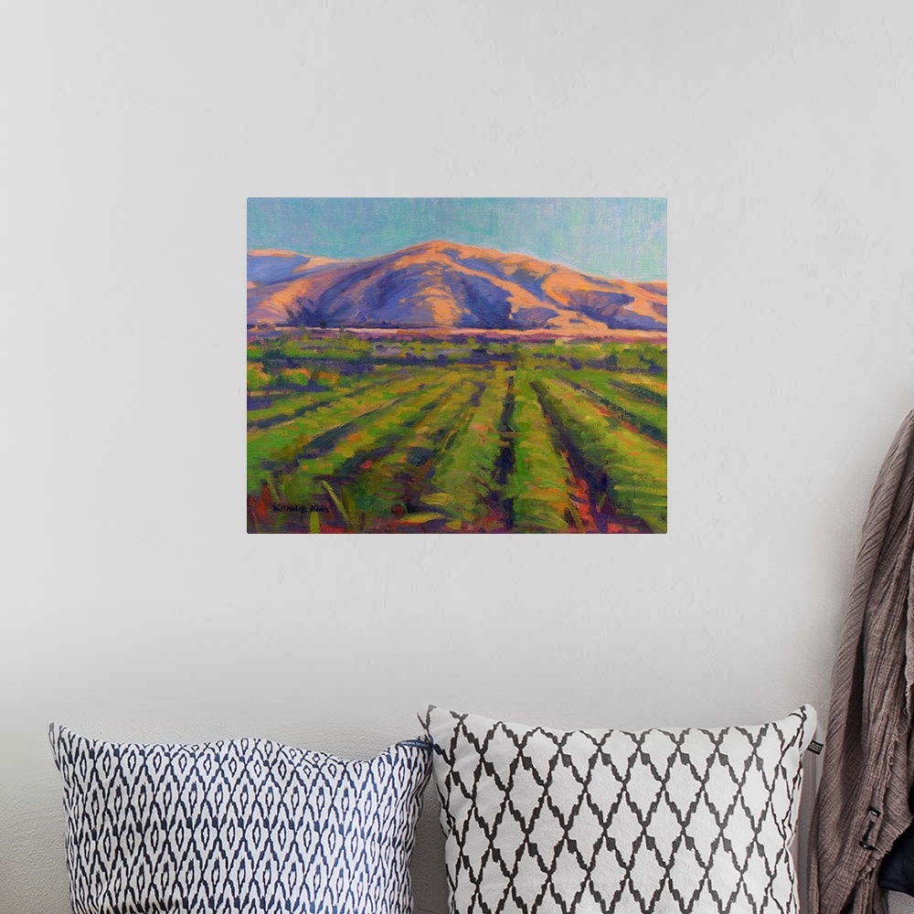 A bohemian room featuring A contemporary painting of fields with mountains in the background.