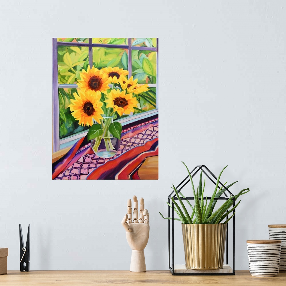 A bohemian room featuring Sunflowers in glass vase on table with plants visible through window.
