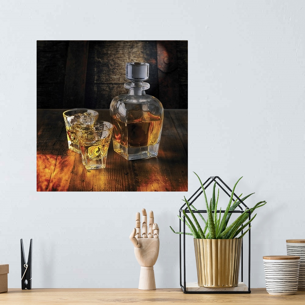 A bohemian room featuring A Whiskey Bottle and Two Glasses on the Rocks on a Wooden Table.