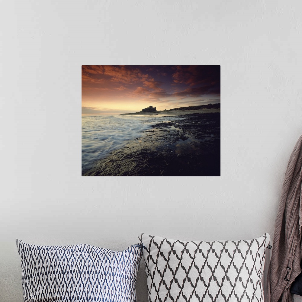 A bohemian room featuring Oversized landscape photograph of a rocky shoreline in England at sunset, Bam burgh Castle can be...