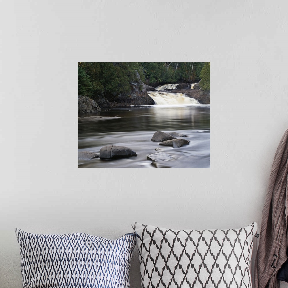 A bohemian room featuring Photograph of two falls flowing into a river that is lined with cliffs and trees on the back side...