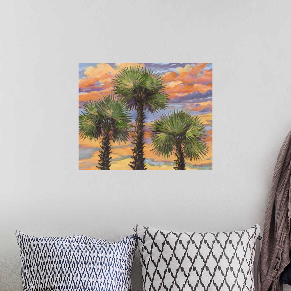 A bohemian room featuring A group of three palm trees against clouds illuminated by the sunset.
