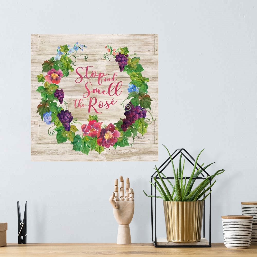 A bohemian room featuring "Stop and Smell the Rose" written in the center of a floral wreath with grapes on a faux wood bac...