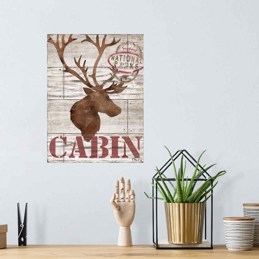 A bohemian room featuring Contemporary decorative artwork of an elk silhouette with the word "cabin" on a textured wooden b...