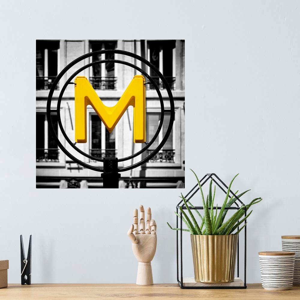 A bohemian room featuring An artistic photograph of a bright yellow M for metro sign against a completely black and white e...