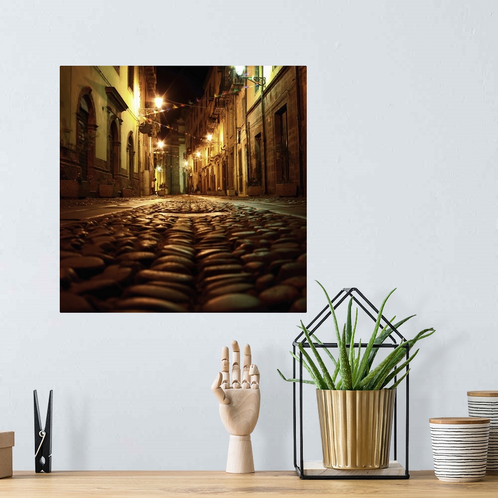 A bohemian room featuring Cobblestone road in the city of Bosa, Italy, at night.
