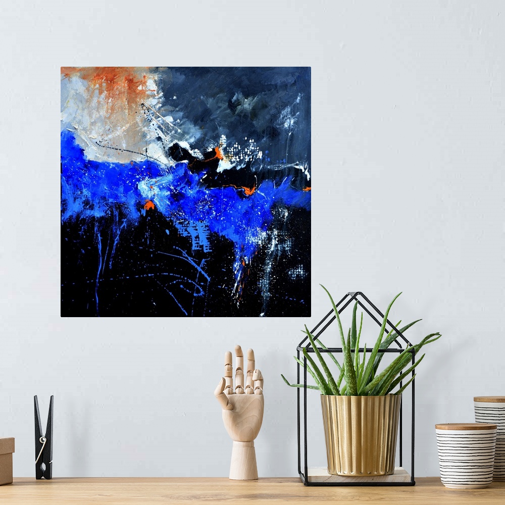 A bohemian room featuring A square abstract painting in shades of black, blue, white and orange with splatters of paint ove...