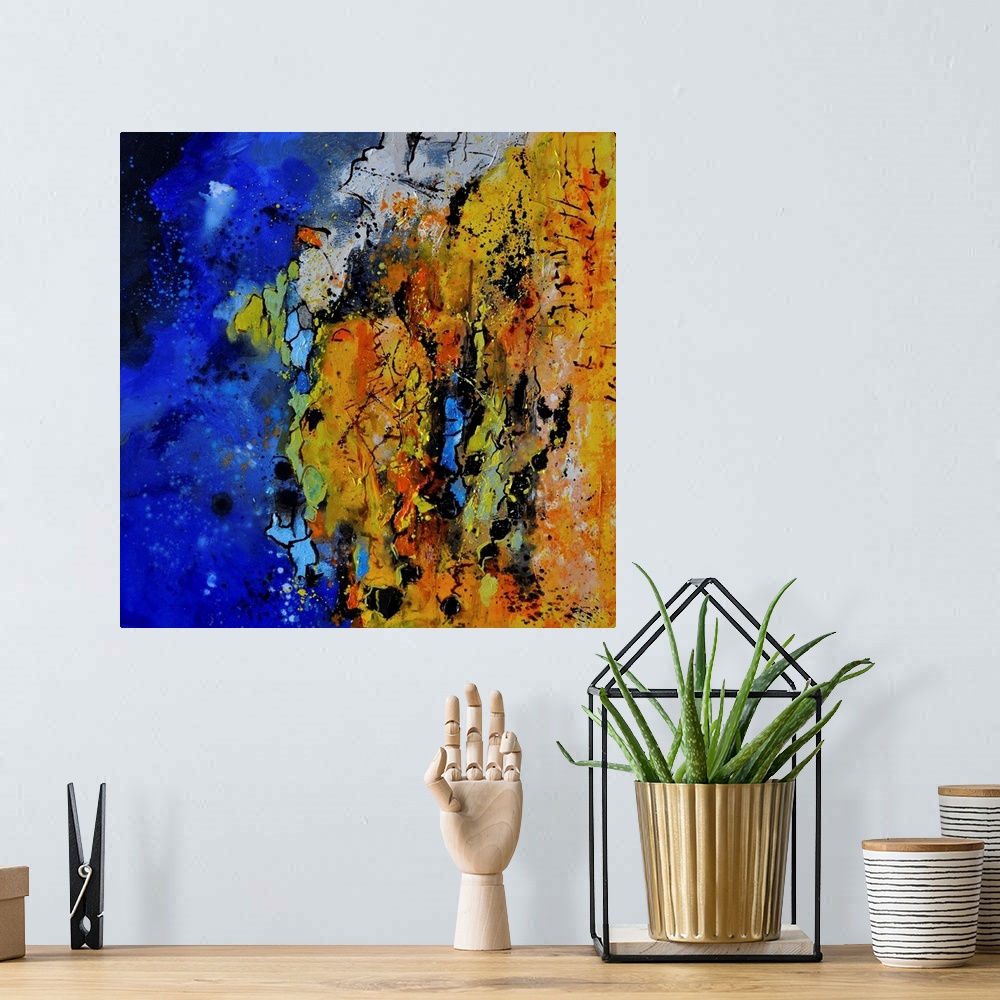A bohemian room featuring A square abstract painting with vibrant colors of blue, orange and yellow.