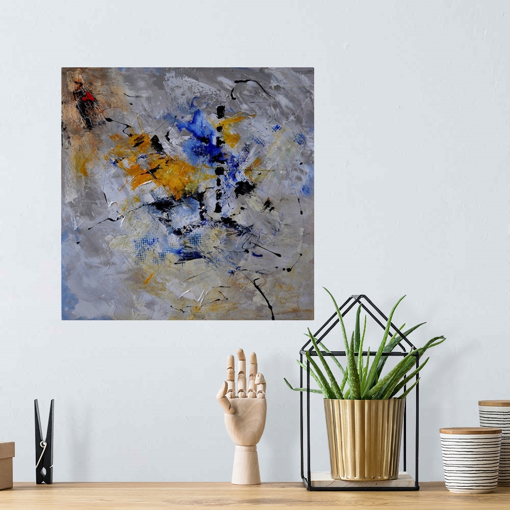 A bohemian room featuring A square abstract painting in dark shades of gray, blue, white and yellow with splatters of paint...
