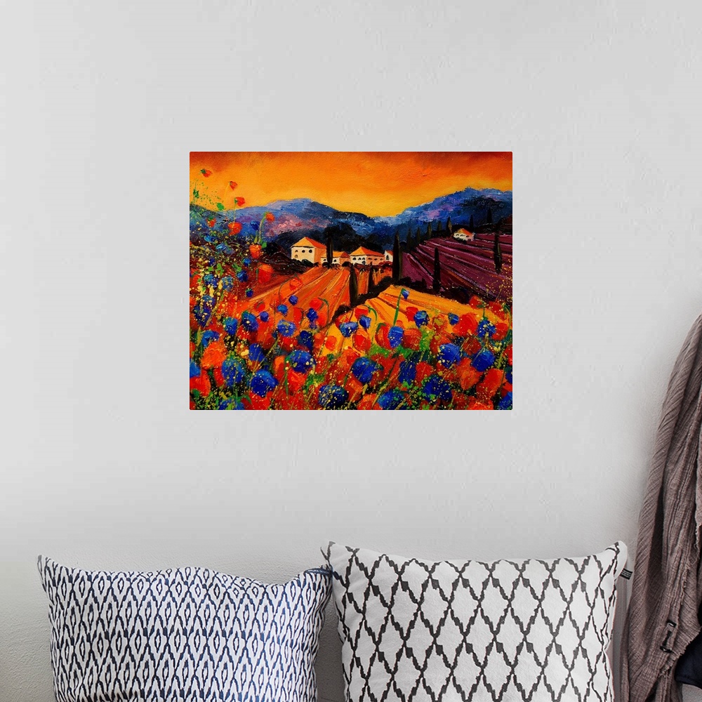 A bohemian room featuring A horizontal painting of rolling fields and houses in rural Tuscany with red and blue poppies in ...
