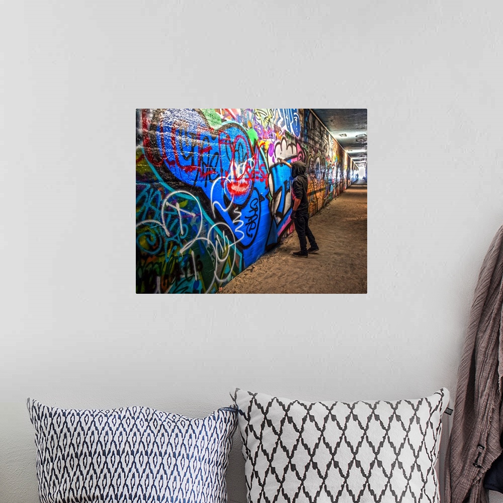 A bohemian room featuring A graffiti artist adds to a mural in the Krog Street Tunnel, which connects Inman Park and Cabbag...