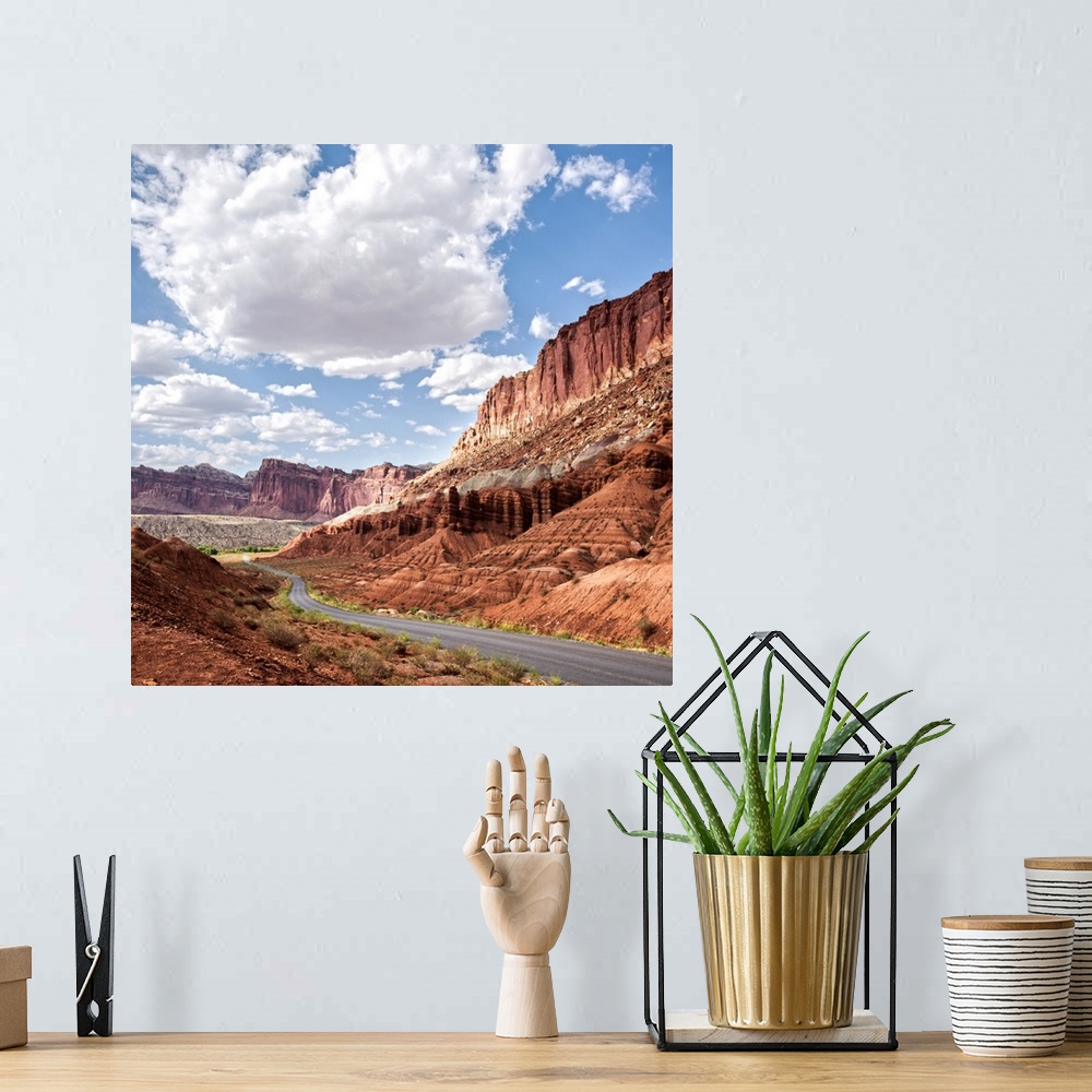 A bohemian room featuring A road winds through Capitol Reef National Park while puffy clouds scatter across a bright blue sky.