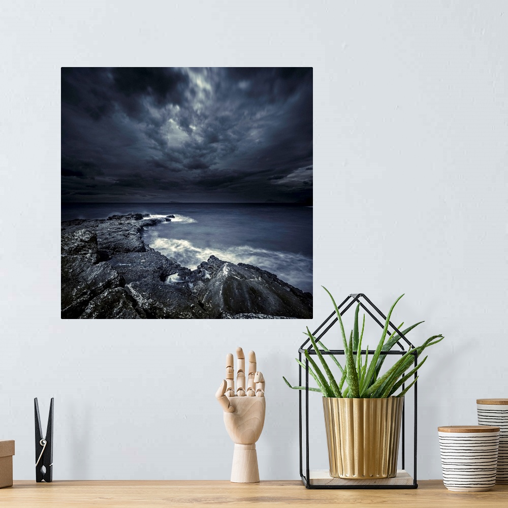 A bohemian room featuring Black rocks protruding through rough seas with stormy clouds, Crete, Greece.
