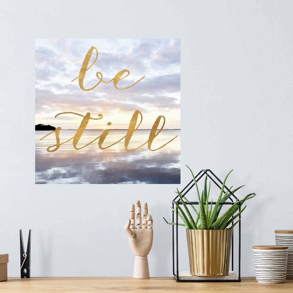 A bohemian room featuring "Be Still" hand written in gold letters over an image of the sea at dawn.