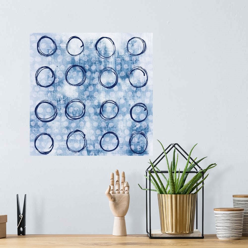 A bohemian room featuring Square abstract painting with indigo outlines of circles in rows in the foreground and smaller, s...