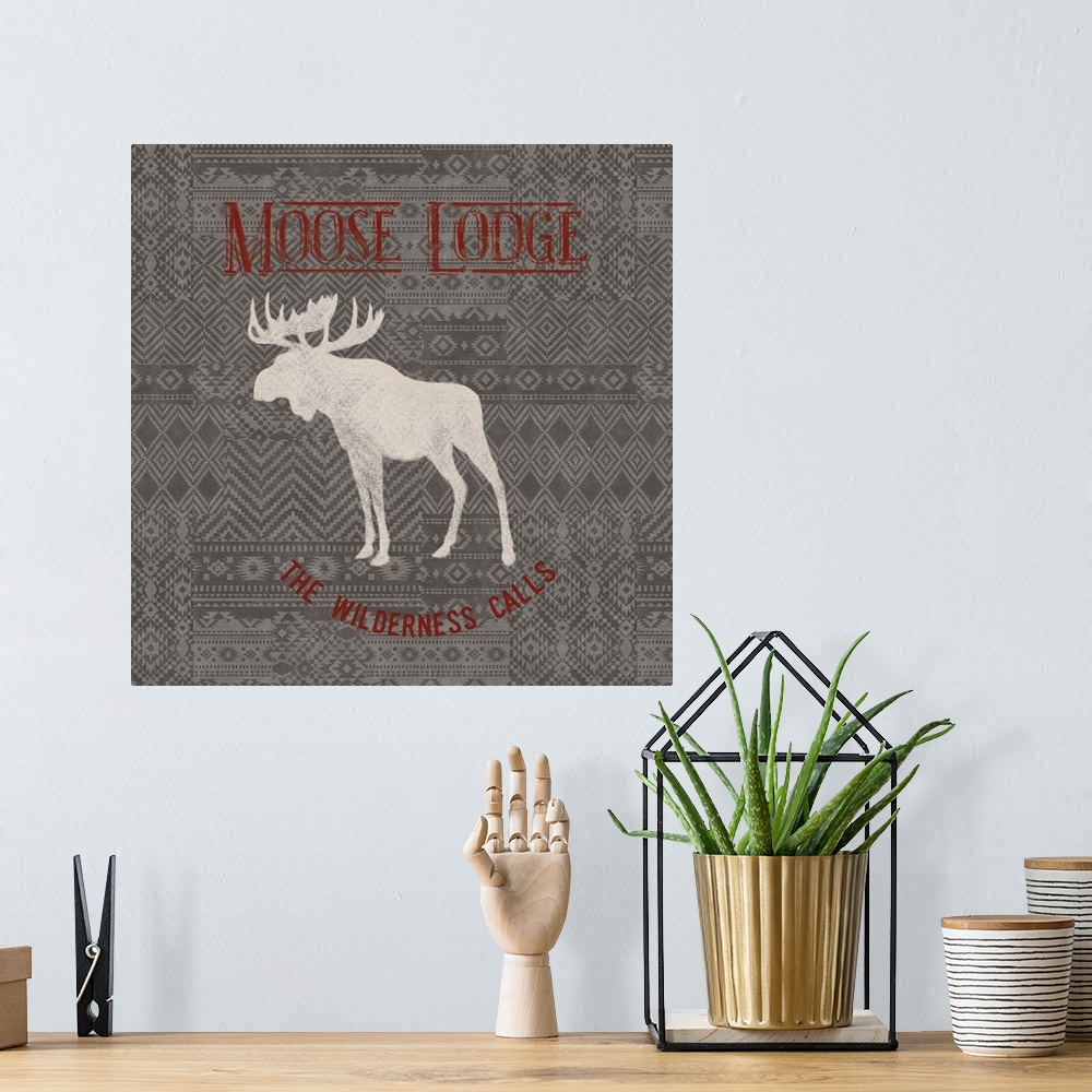 A bohemian room featuring "Moose Lodge" "The Wilderness Calls" written in red on a gray patterned background with a white s...