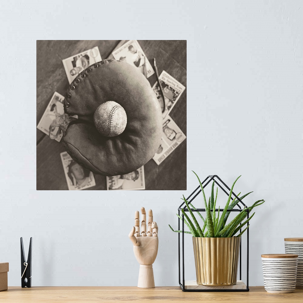 A bohemian room featuring Square sepia toned photograph of a worn baseball in an old mitt and vintage baseball cards behind...
