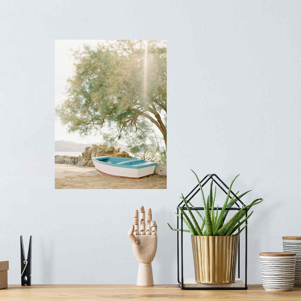 A bohemian room featuring Photograph of a small wooden boat underneath a tree next to the water, Milos, Greece.