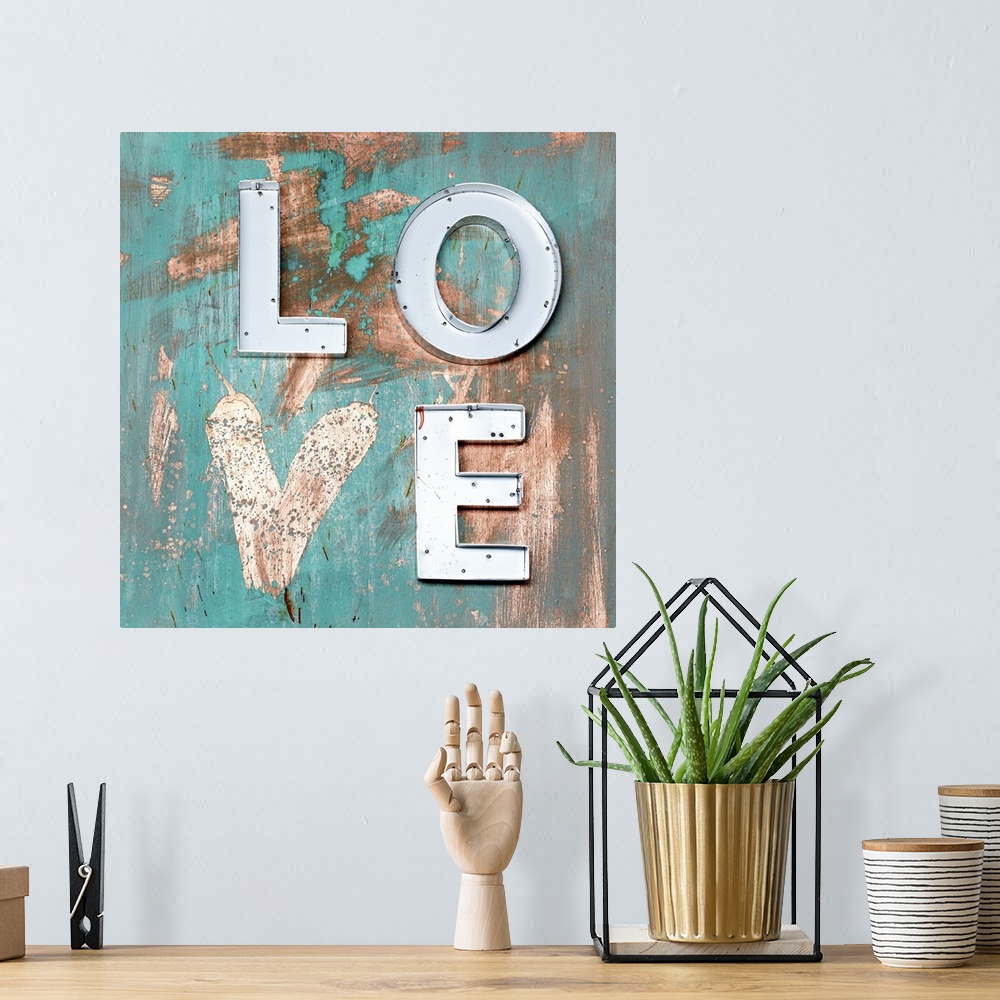 A bohemian room featuring The word "Love" made of metal letters and a painted heart on weathered teal boards.