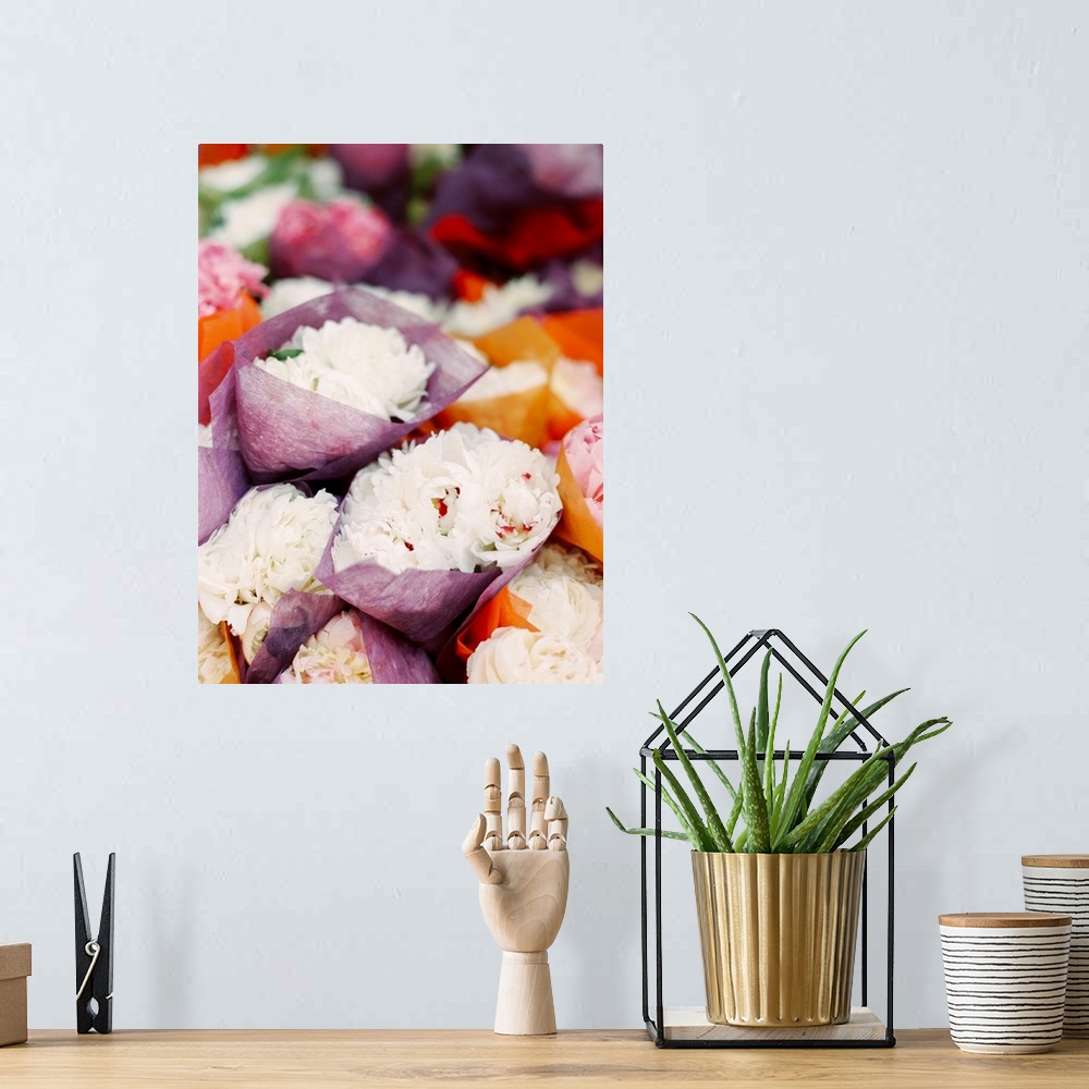 A bohemian room featuring Photograph of bunches of white peony flowers crapped in tissue paper in a market.